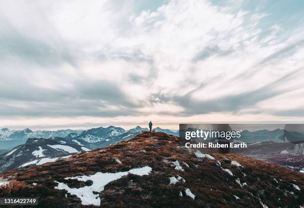 woman hiker stands in the top of a mountain in winter at sunset feeling free - aerial view of clouds and earth landscape stock pictures, royalty-free photos & images