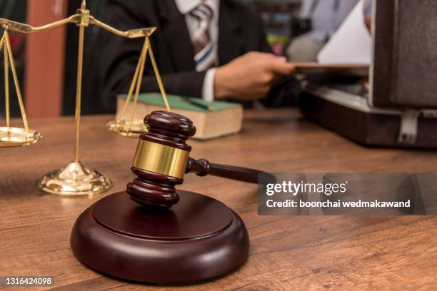 tribunal attorney lawyer working with documents and wooden judge gavel on table in courtroom. - judges table stock pictures, royalty-free photos & images