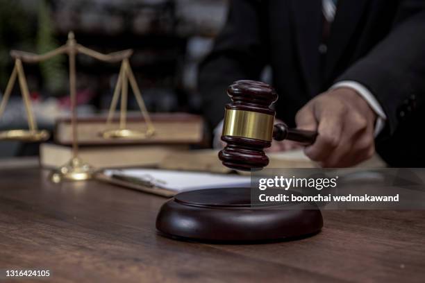 man hand knocking a wooden judge gavel, law and auction concept. - auctioneer stock-fotos und bilder