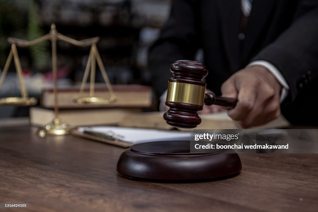 Man hand knocking a wooden judge gavel, law and auction concept.