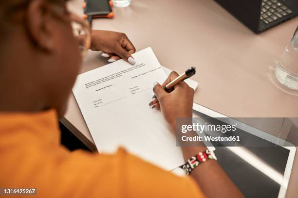 businesswoman signing contract at desk in office - overeenkomst stockfoto's en -beelden