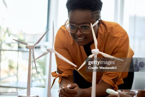 woman wearing eyeglasses examining wind turbine models at office - architekt mit plan frontal stock-fotos und bilder