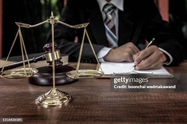 tribunal attorney lawyer working with documents and wooden judge gavel on table in courtroom. - criminal lawyer stock pictures, royalty-free photos & images