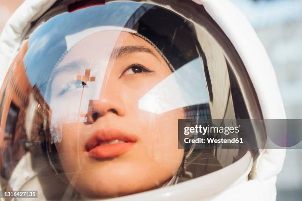 female astronaut looking away through space helmet during sunny day - casco espacial fotografías e imágenes de stock