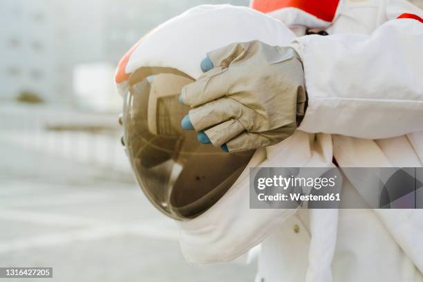 female astronaut holding space helmet - glove stock-fotos und bilder