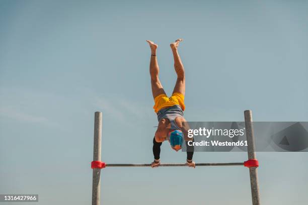 male gymnast doing handstand on high bar - reck stock-fotos und bilder