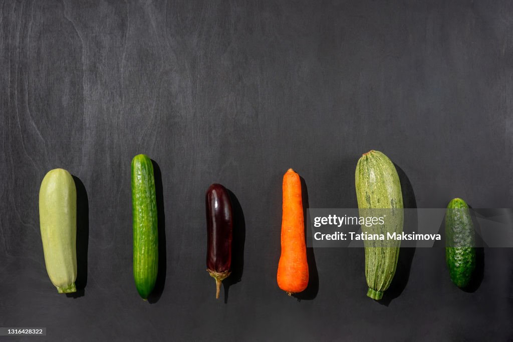 Various fresh vegetables rows on black background. Vegetarian food.