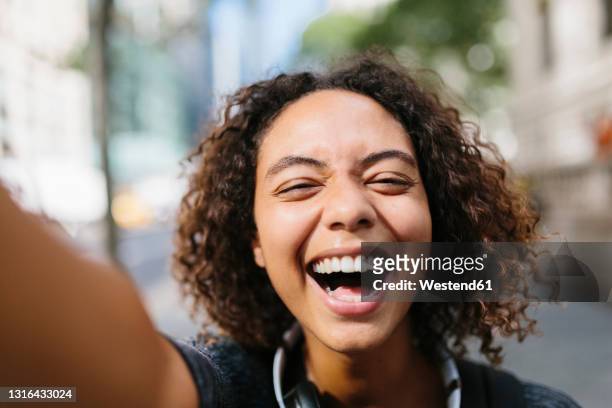 laughing young woman taking selfie in city - geöffneter mund stock-fotos und bilder