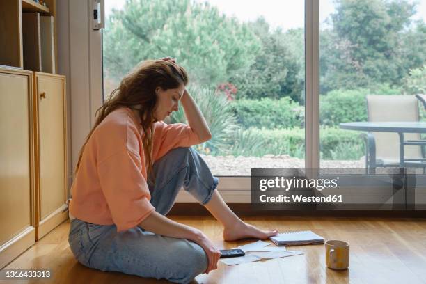 woman with head in hands looking at bills and receipts while sitting at home - long receipt stock pictures, royalty-free photos & images