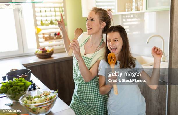 young mother and daughter having fun singing in the kitchen - mother food imagens e fotografias de stock