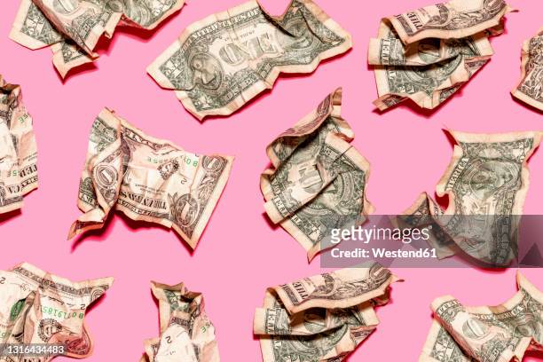 pattern of crumpled one dollar bills lying against pink background - crumpled stock pictures, royalty-free photos & images