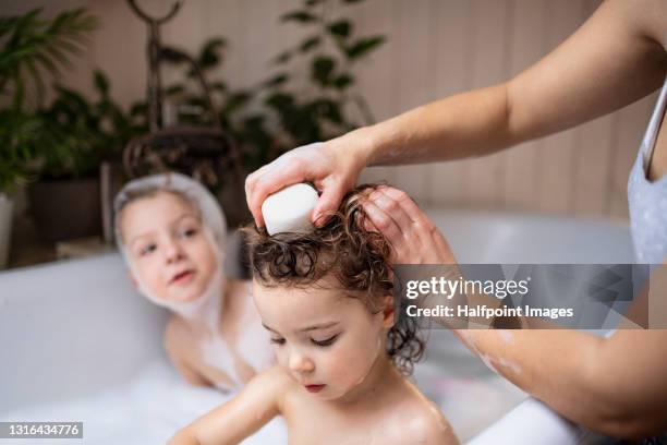 small children in bath at home, mother washing hair with dry shampoo. - kid bath mother stock-fotos und bilder