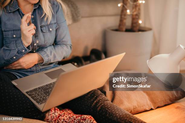 vrouw die vingers kruist terwijl het zitten met laptop - house auction stockfoto's en -beelden