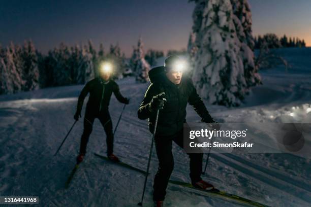 mensen die op sneeuw bij nacht skiën - hoofdlamp stockfoto's en -beelden