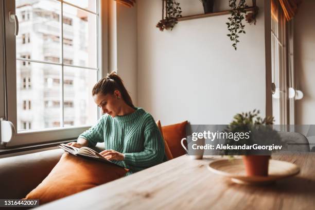 female looking at old photo album in home kitchen - home interior stock pictures, royalty-free photos & images