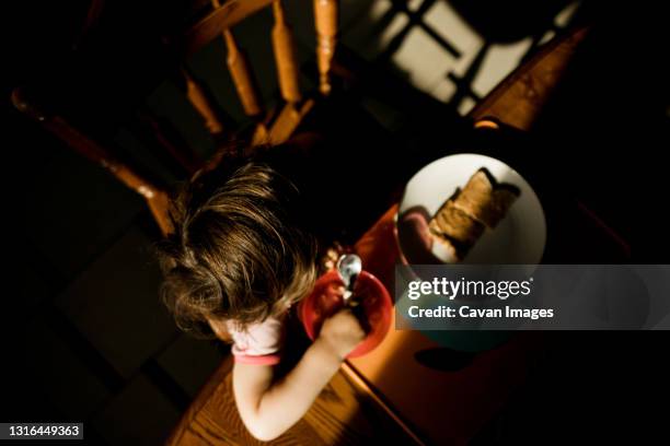overhead view of a young girl eating her breakfast at kitchen table - frühstück von oben stock-fotos und bilder