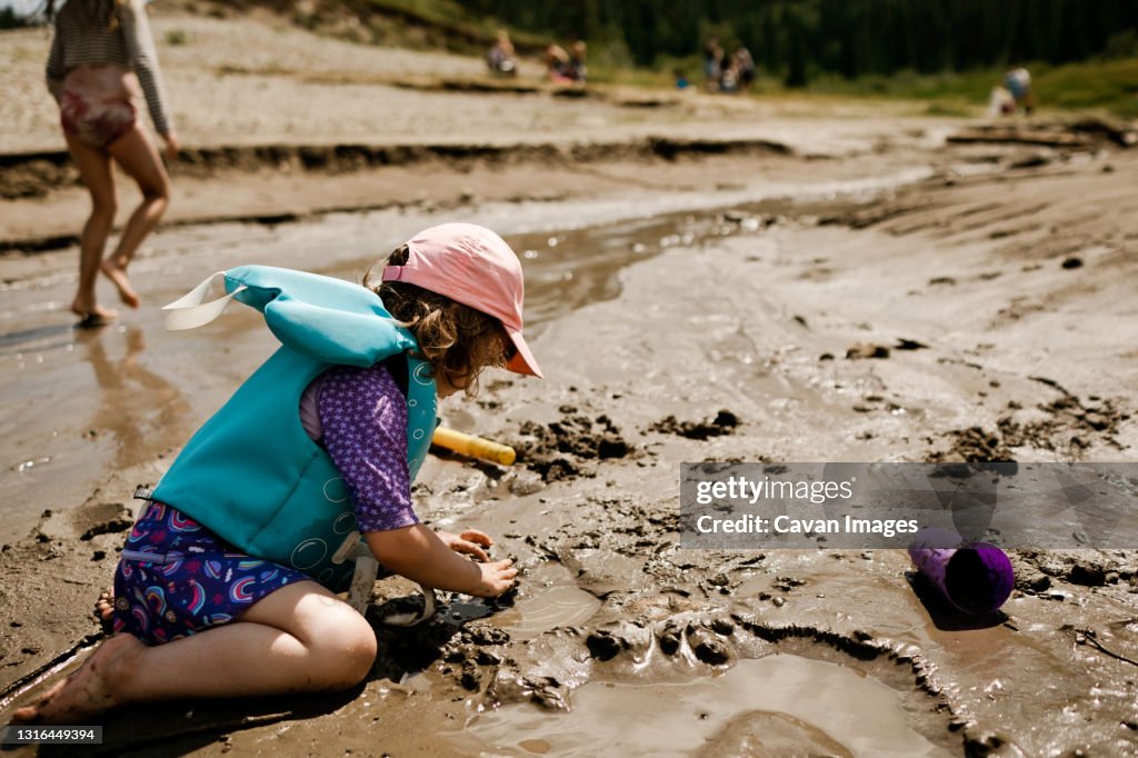 Young girl playing at the beach making a sand castle in the summer