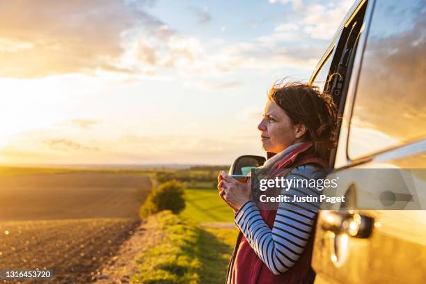 woman looking at the view from her campervan - gelassene person stock-fotos und bilder