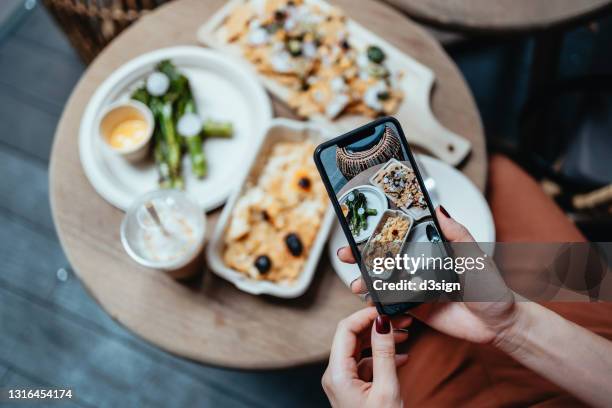 personal perspective of young woman enjoying her home delivery takeaway meal in the balcony, taking photos of delicious food with smartphone before eating it. eating in lifestyle. camera eats first culture. technology in everyday life - mexican food catering stock pictures, royalty-free photos & images
