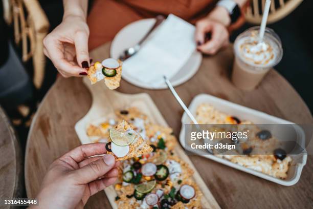 personal perspective of young couple having a good time enjoying meal at sidewalk cafe, sharing freshly served nacho chips and cheese macaroni together. social gathering. eating out lifestyle - mexican food catering stock pictures, royalty-free photos & images