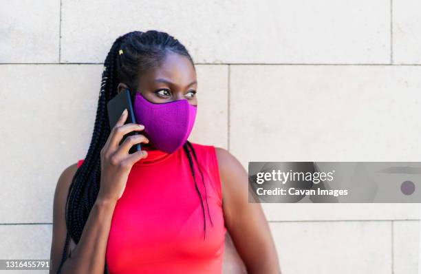 african woman athlete talking from her smartphone - lateral portrait looking mobile photos et images de collection