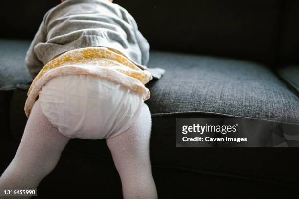 detail of one year old girl climbing onto couch - baby po stock-fotos und bilder