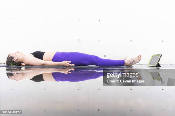 athlete woman doing the savasana posture during an online yoga class - savasana stock pictures, royalty-free photos & images