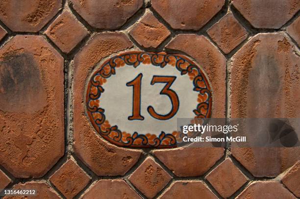 number 13 street address handpainted on a glazed tile on a eroded terracotta tile wall - house number stock pictures, royalty-free photos & images