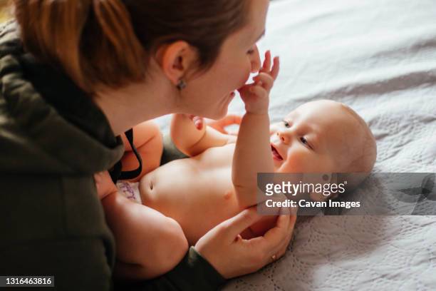 adorable naked baby examines mother's face - kids in diapers - fotografias e filmes do acervo