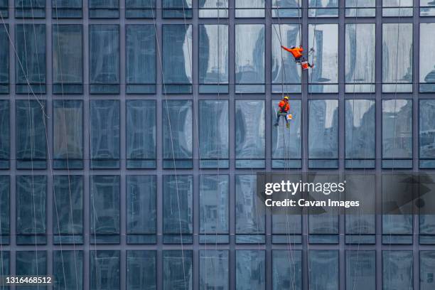 window cleaner's working on facade of high rise building in bangkok - limpador de janela - fotografias e filmes do acervo