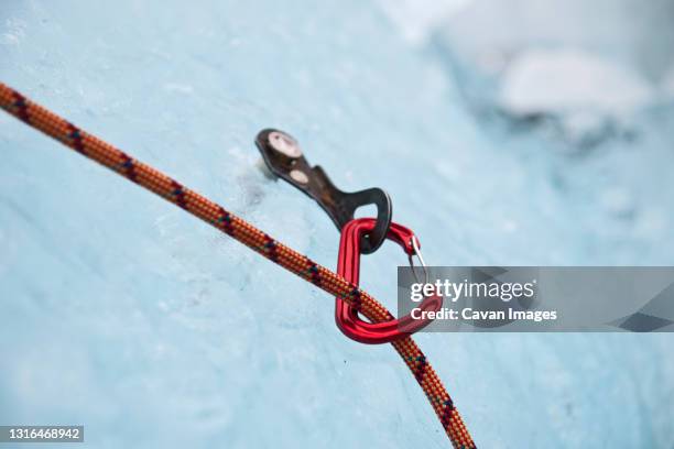 karabiner attached to ice screw on iceberg in the south of iceland - carabiner stockfoto's en -beelden