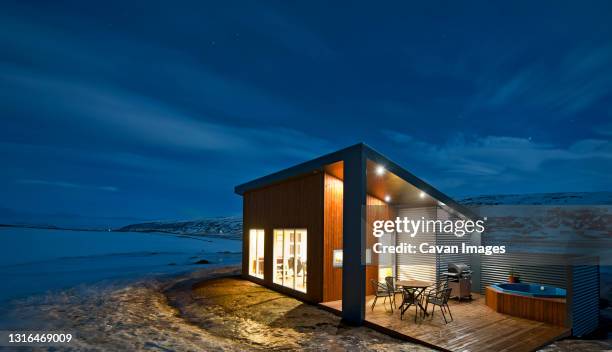 illuminated holiday home in iceland during the winter - modern house dusk stock-fotos und bilder