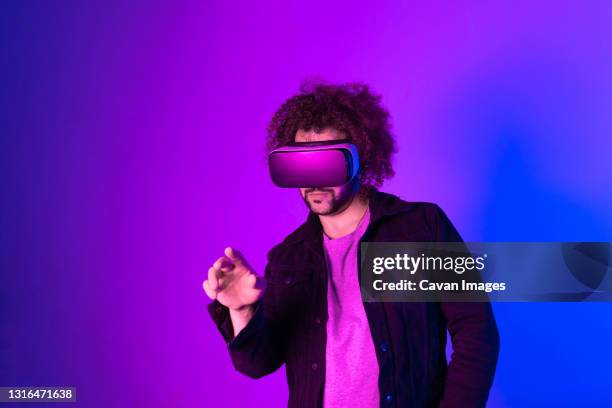 hipster young man using virtual reality headset over blue purple - virtual reality simulator - fotografias e filmes do acervo