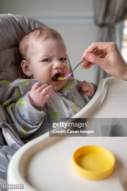 baby boy taking a bite of avocado. - baby eating toy foto e immagini stock