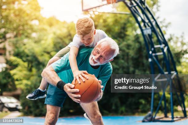 grootvader en kleinzoon op basketbalhof - kids playing basketball stockfoto's en -beelden