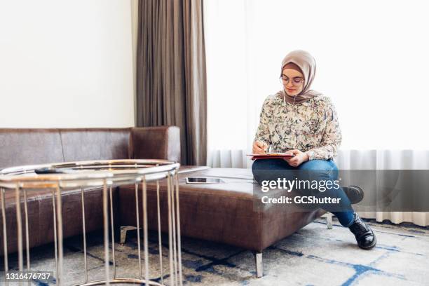 de jonge vrouw die van het midden-oosten nota's voorbereidt - woman filling out paperwork stockfoto's en -beelden