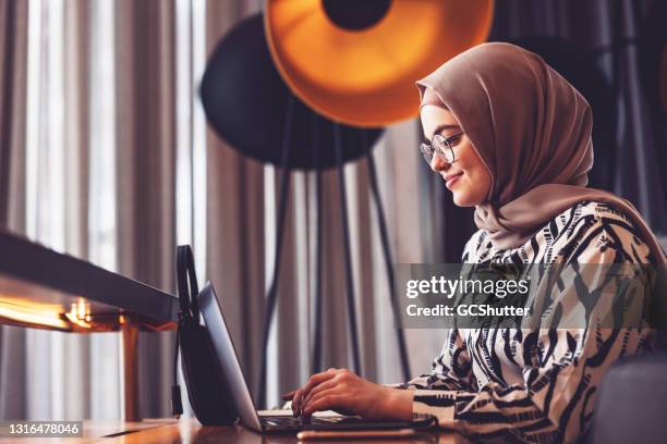 het meisje dat van het middenoosten laptop gebruikt om online te bank - modern arab woman stockfoto's en -beelden