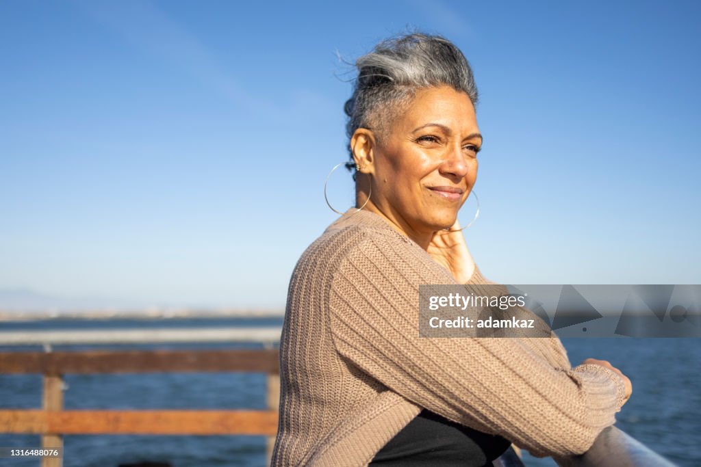 Reife schwarze Frau entspannen donerisch am Pier
