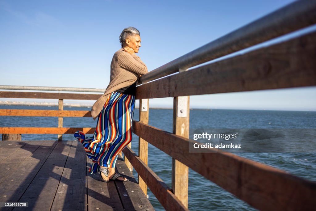 Reife schwarze Frau entspannen donerisch am Pier