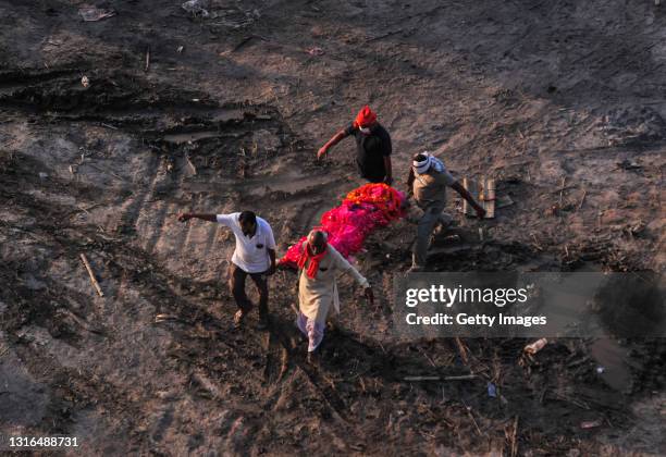 Relatives carry a body of a relative who was thought to have died of Covid-19 to a funeral pyre at a mass crematorium site on the banks of the Ganges...