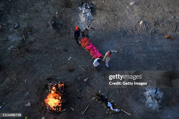 Relatives carry a body of a relative who was thought to have died of Covid-19 to a funeral pyre at a mass crematorium site on the banks of the Ganges...