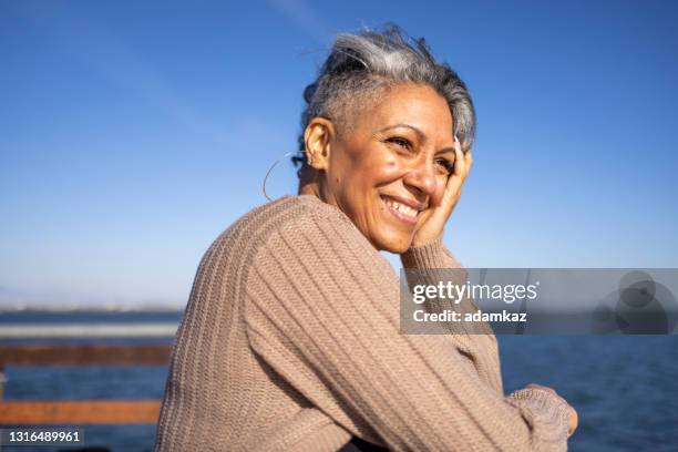 mujer negra madura relajándose en el muelle - gray hair fotografías e imágenes de stock