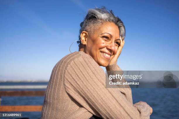 donna nera matura che si rilassa al molo - stupore esterno foto e immagini stock