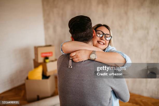 joyful young couple embracing in new apartment - home ownership keys stock pictures, royalty-free photos & images