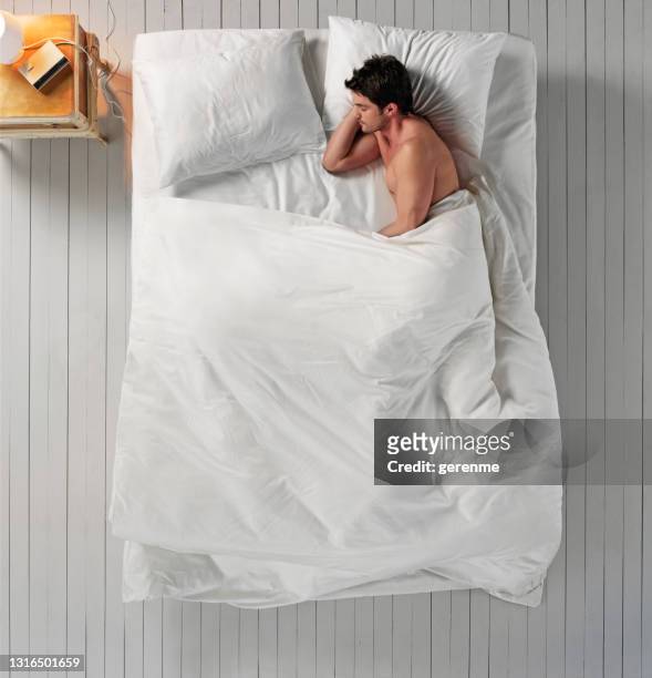 schlafen im bett - above view of man sleeping on bed stock-fotos und bilder