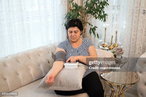 先輩女性は自宅で彼女の血圧を測定します - high blood pressure ストックフォトと画像