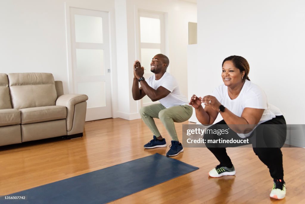 Mature adult couple doing exercise at home.