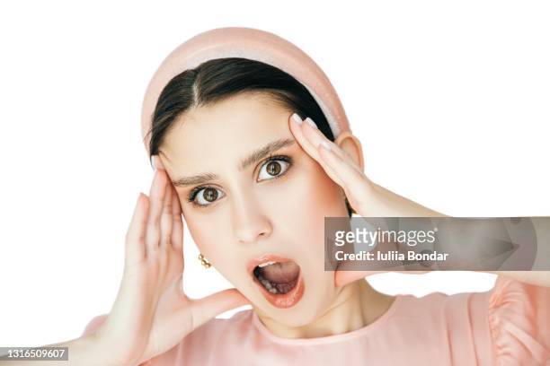 close-up portrait of surprised beautiful girl holding her head in amazement and open-mouthed. - beautiful woman shocked stock pictures, royalty-free photos & images