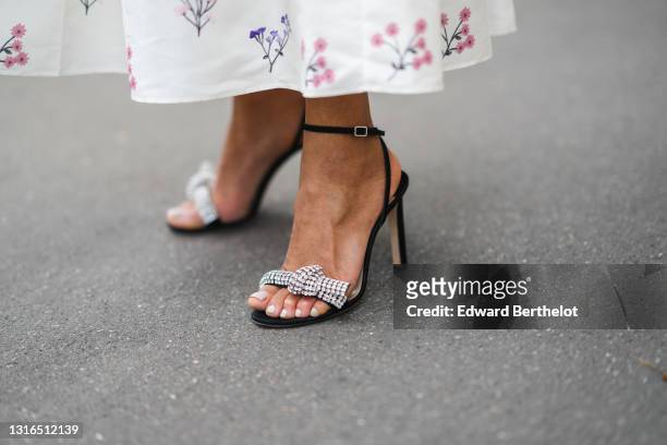 Ellie Delphine wears a white with navy blue and pink flower pattern long Self Portrait dress, black strapped Jimmy Choo pumps with a rhinestones bow...