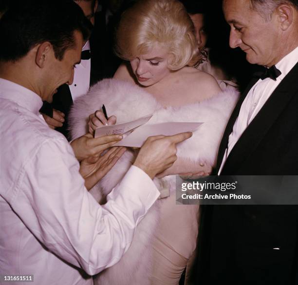 American actress Marilyn Monroe signs autographs for fans, circa 1959.